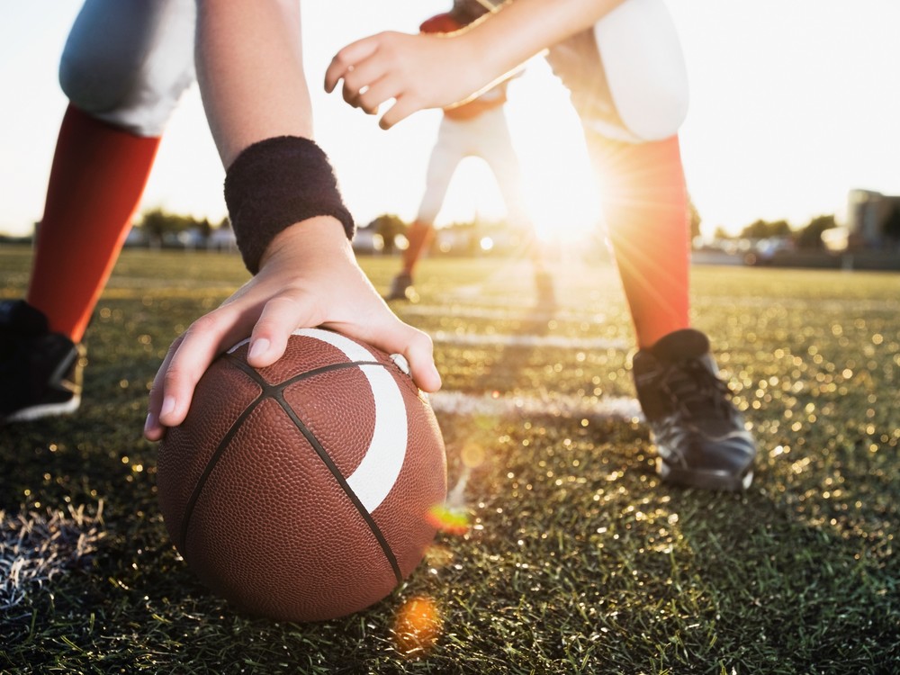 close up of football player's hand on football before hiking the ball